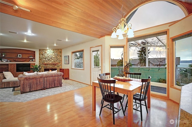 dining room featuring wooden ceiling, light wood-type flooring, built in features, a fireplace, and a chandelier