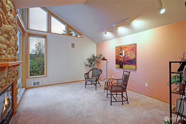 sitting room with light carpet, a fireplace, rail lighting, and high vaulted ceiling