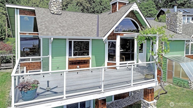 337 Moana Dr, Camano Island, WA 98282 - back of property featuring roof with shingles, a deck, a greenhouse, and a chimney