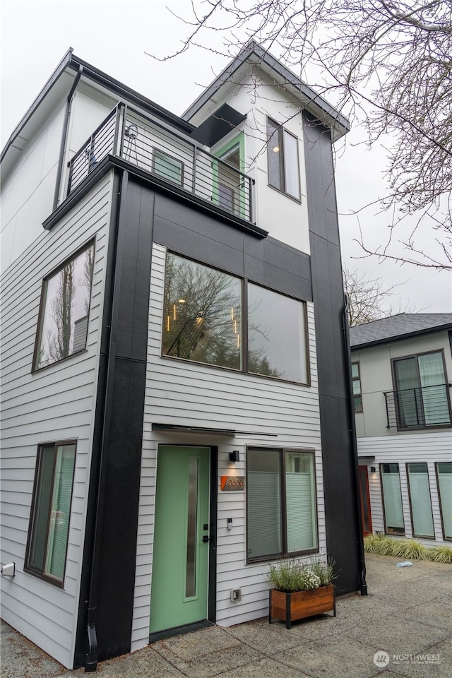 view of front of property with elevator and a balcony