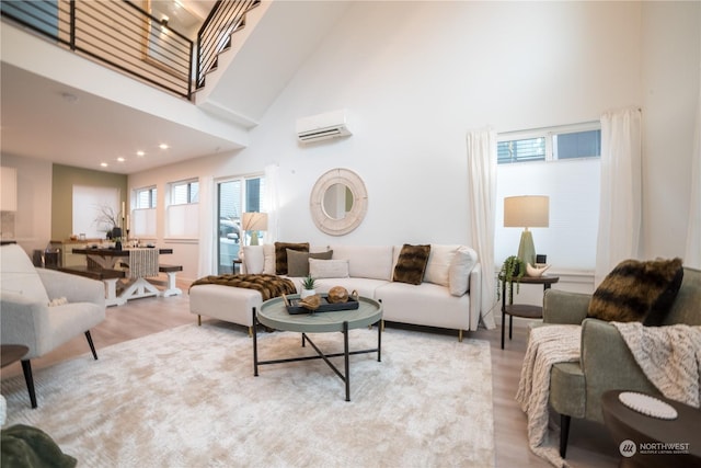 living room featuring a wall mounted air conditioner, a towering ceiling, and light hardwood / wood-style flooring