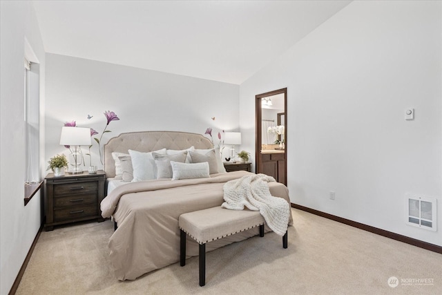 carpeted bedroom with lofted ceiling and ensuite bath