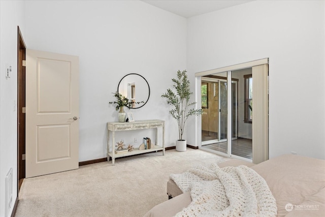 bedroom with access to exterior, a towering ceiling, and light carpet