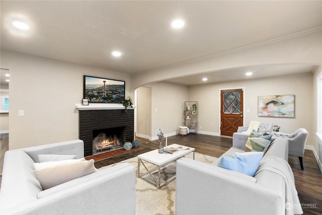 living room featuring dark hardwood / wood-style floors, ornamental molding, and a fireplace