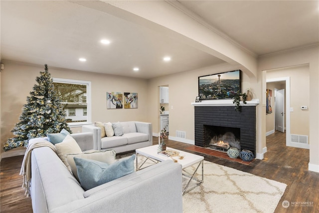 living room with dark hardwood / wood-style floors, crown molding, and a brick fireplace