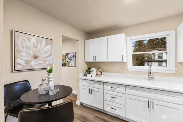 kitchen with hardwood / wood-style flooring, white cabinetry, and sink