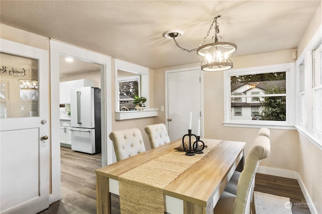 dining space with wood-type flooring, a textured ceiling, and a notable chandelier