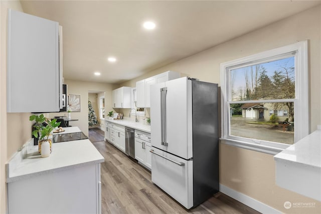 kitchen featuring white cabinets, light hardwood / wood-style floors, stainless steel dishwasher, and high end refrigerator