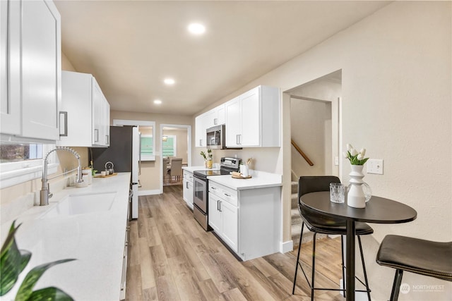 kitchen featuring sink, white cabinets, light hardwood / wood-style floors, and appliances with stainless steel finishes