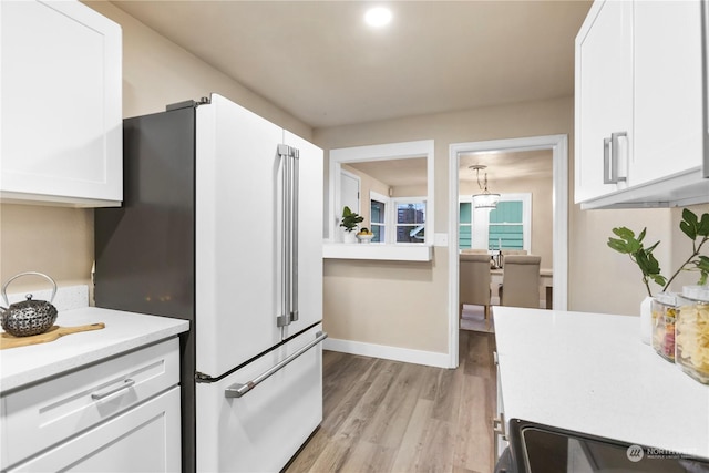 kitchen featuring white cabinets, stove, light wood-type flooring, and high quality fridge