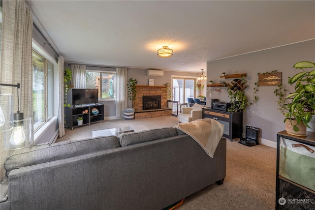 living room with an AC wall unit, a stone fireplace, a chandelier, and light colored carpet