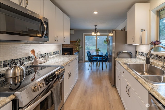 kitchen with sink, white cabinetry, an inviting chandelier, pendant lighting, and appliances with stainless steel finishes