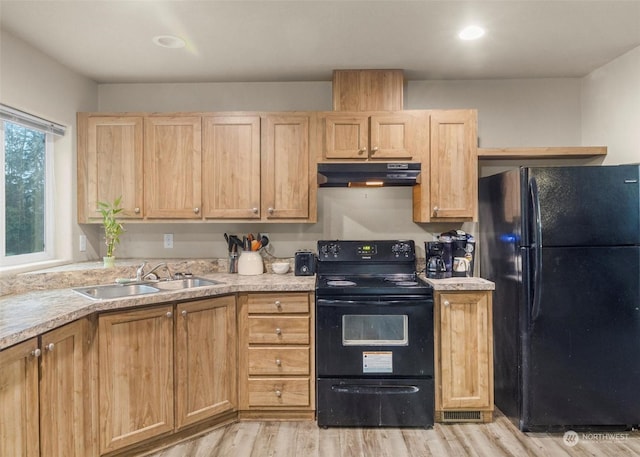 kitchen with light brown cabinetry, sink, black appliances, and light hardwood / wood-style flooring