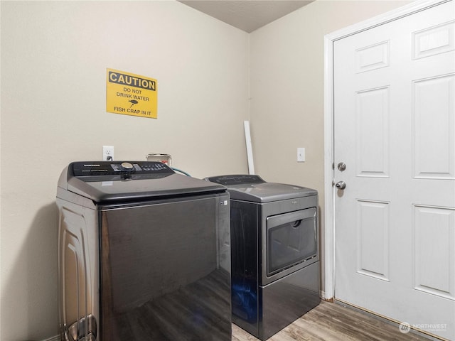 laundry area with washing machine and clothes dryer and hardwood / wood-style flooring