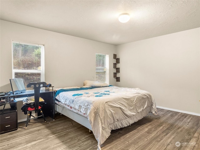 bedroom with wood-type flooring, a textured ceiling, and multiple windows