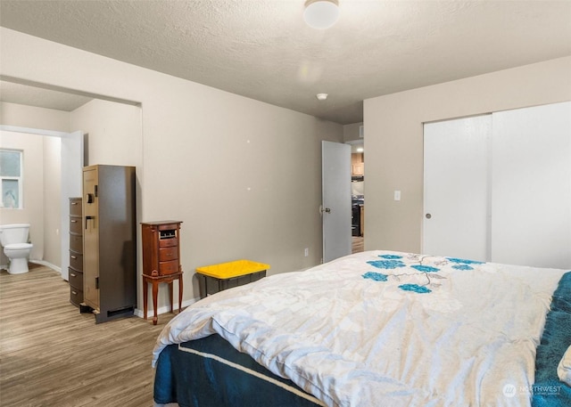 bedroom with connected bathroom, hardwood / wood-style flooring, and a closet