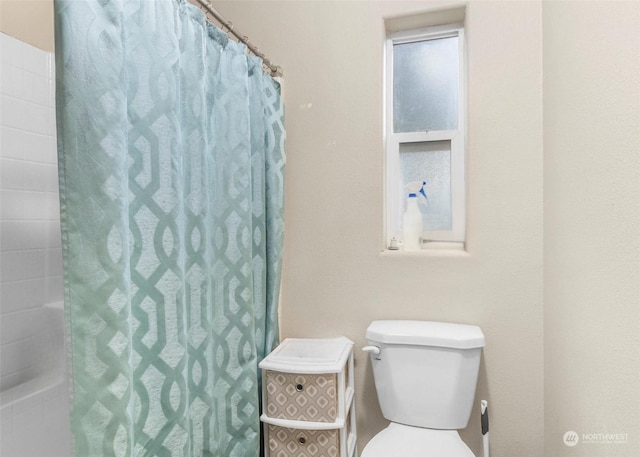 bathroom featuring toilet and curtained shower