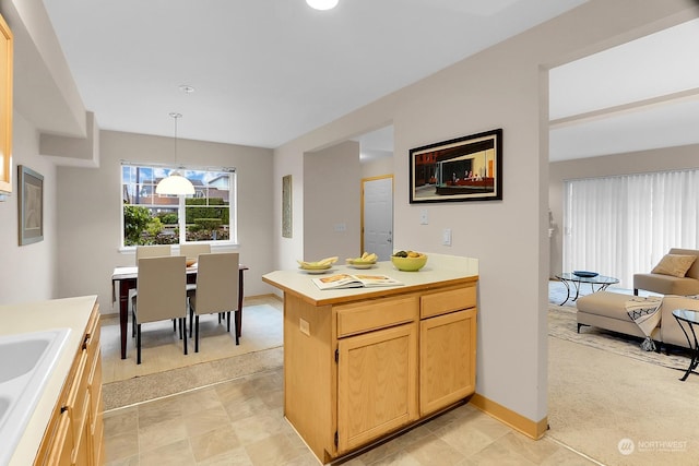 kitchen with light carpet, light brown cabinets, hanging light fixtures, and sink