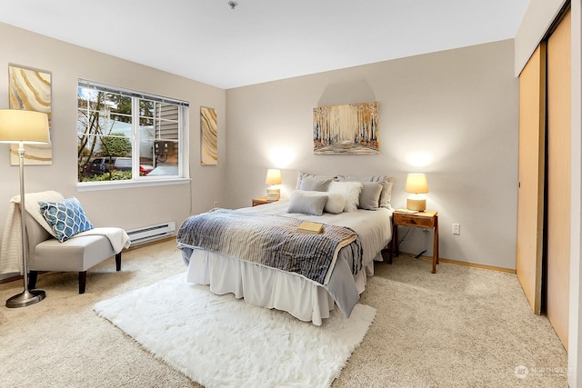 carpeted bedroom featuring baseboard heating and a closet