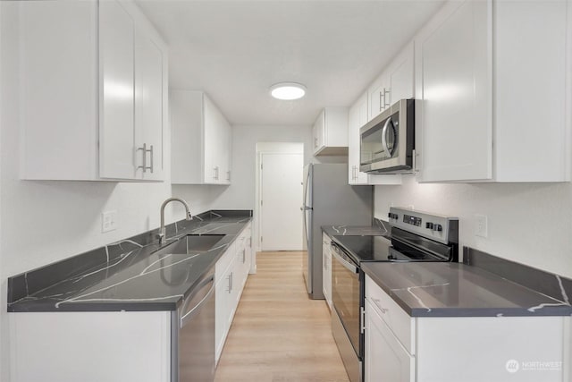 kitchen with white cabinetry, sink, light hardwood / wood-style flooring, and appliances with stainless steel finishes