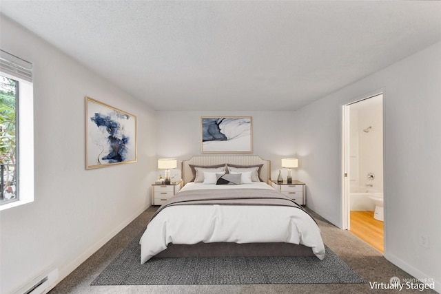 carpeted bedroom with ensuite bathroom and baseboard heating