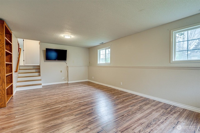 basement featuring a textured ceiling and light hardwood / wood-style floors