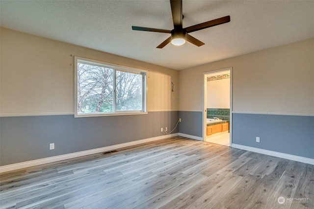 spare room with ceiling fan, a textured ceiling, and light hardwood / wood-style flooring