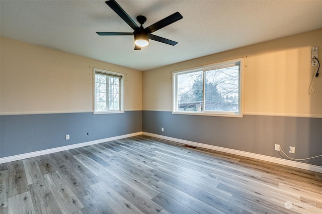 spare room with a textured ceiling, light wood-type flooring, and ceiling fan