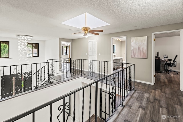 hallway with a skylight, a chandelier, dark wood-type flooring, and a textured ceiling