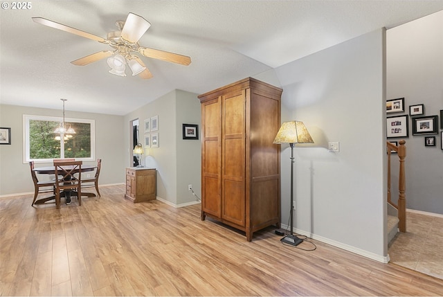 interior space featuring a textured ceiling, ceiling fan with notable chandelier, and light wood-type flooring