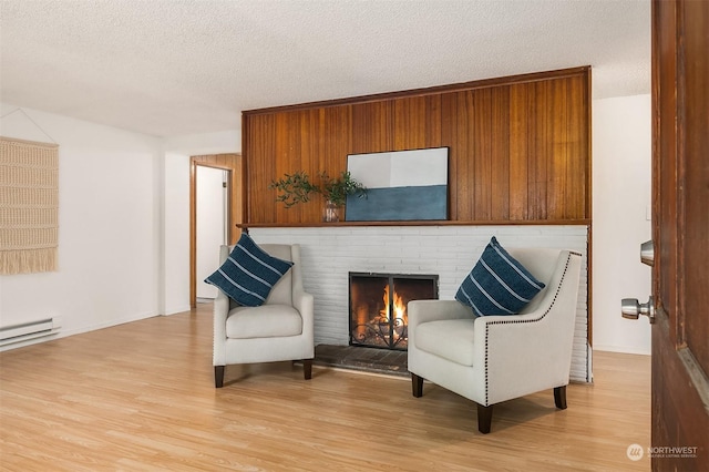 sitting room with a fireplace, a textured ceiling, and light hardwood / wood-style flooring