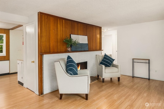 sitting room featuring light wood-type flooring, a textured ceiling, and a fireplace