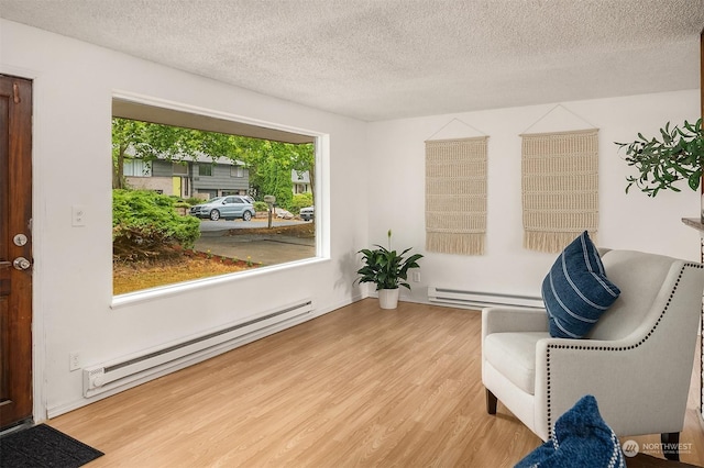 sitting room with light hardwood / wood-style floors, a textured ceiling, and a baseboard heating unit