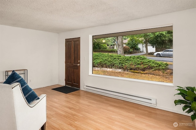 living area featuring hardwood / wood-style floors, a baseboard radiator, and a textured ceiling