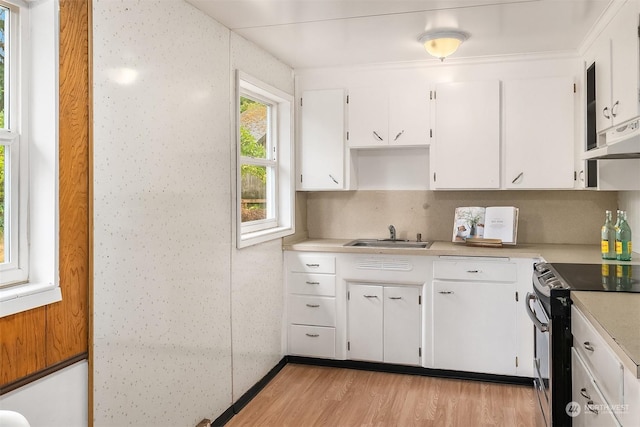 kitchen with white cabinetry, sink, tasteful backsplash, light hardwood / wood-style flooring, and stainless steel range with electric cooktop