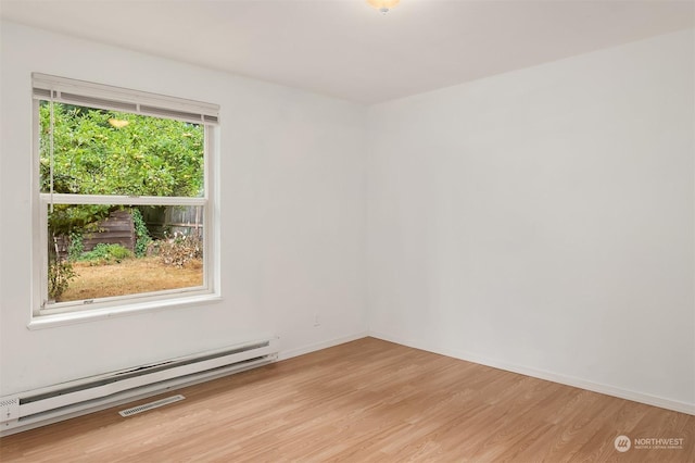 empty room with baseboard heating and light hardwood / wood-style flooring