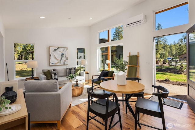 dining area featuring an AC wall unit, light wood-type flooring, recessed lighting, and a towering ceiling