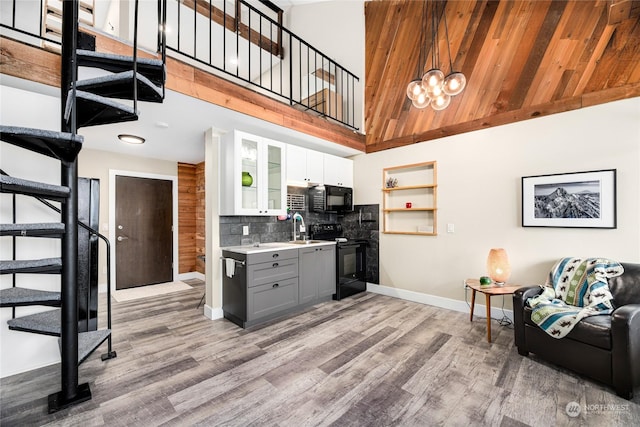 kitchen featuring gray cabinetry, hanging light fixtures, a high ceiling, white cabinets, and black appliances