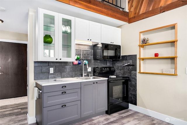 kitchen with tasteful backsplash, dark hardwood / wood-style flooring, gray cabinets, white cabinets, and black appliances