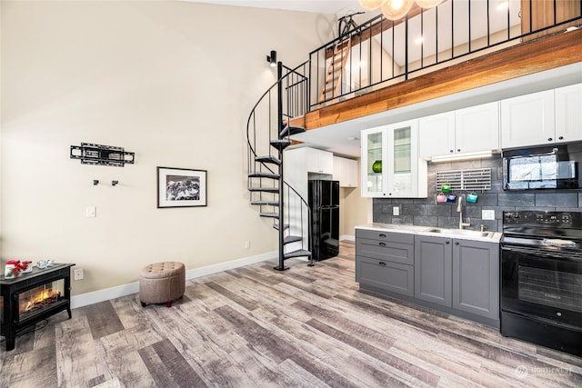 kitchen featuring light wood-type flooring, sink, black appliances, gray cabinets, and white cabinetry