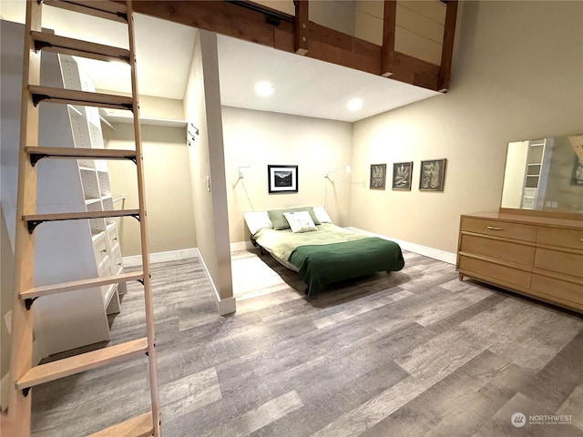 bedroom featuring wood-type flooring and a towering ceiling