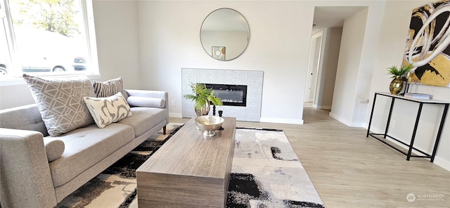 living room featuring a tile fireplace and light hardwood / wood-style flooring