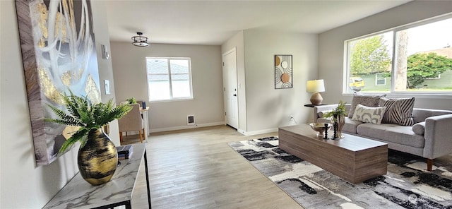 living area featuring baseboards, visible vents, and light wood-style floors