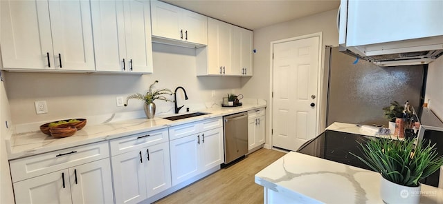 kitchen with light stone counters, a sink, white cabinetry, stainless steel dishwasher, and light wood finished floors