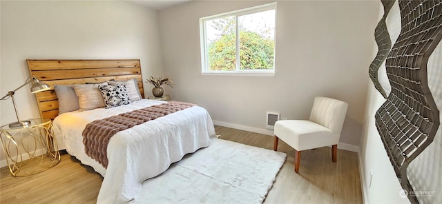 bedroom featuring baseboards, visible vents, and wood finished floors