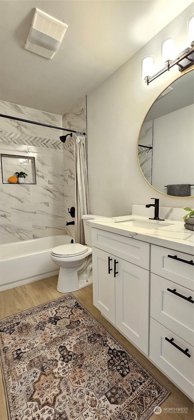 full bathroom featuring shower / bath combination with curtain, visible vents, toilet, vanity, and wood finished floors