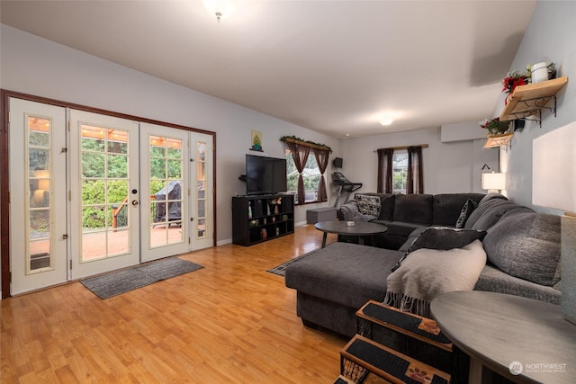 living room with french doors, light wood-type flooring, a wall unit AC, and plenty of natural light