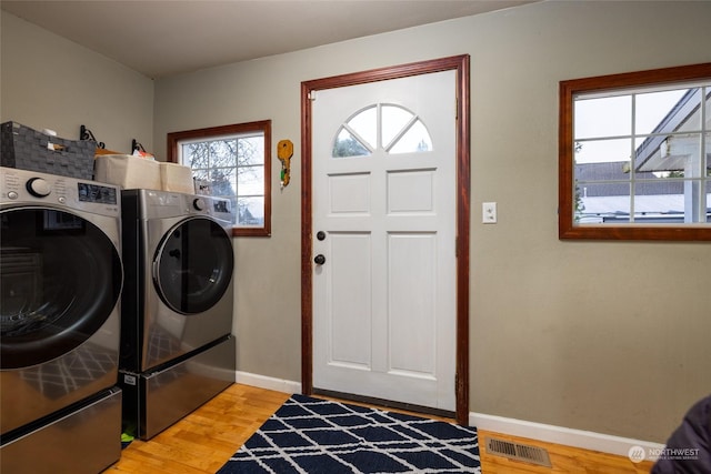 washroom with washer and clothes dryer and light hardwood / wood-style flooring