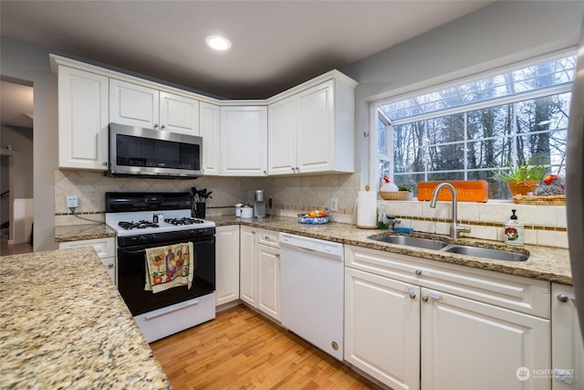 kitchen featuring white cabinetry, sink, tasteful backsplash, white appliances, and light wood-type flooring