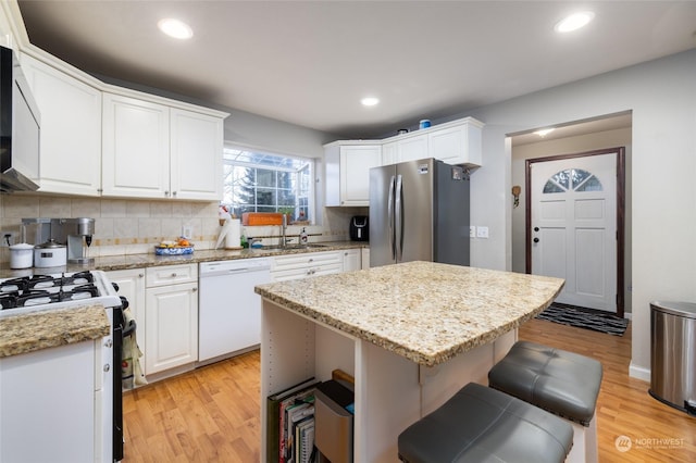 kitchen with tasteful backsplash, white cabinetry, a kitchen island, and white appliances